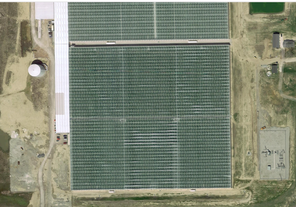 Aerial view of a large commercial greenhouse and supporting site infrastructure