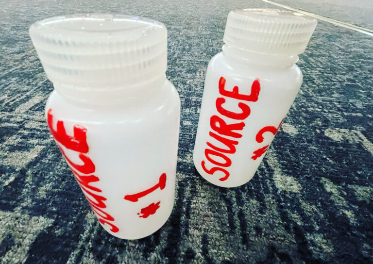 Hydroponic water testing samples in two bottles identified by water source